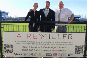 Airey Miller and Bromley FC team in front of Airey Miller sign